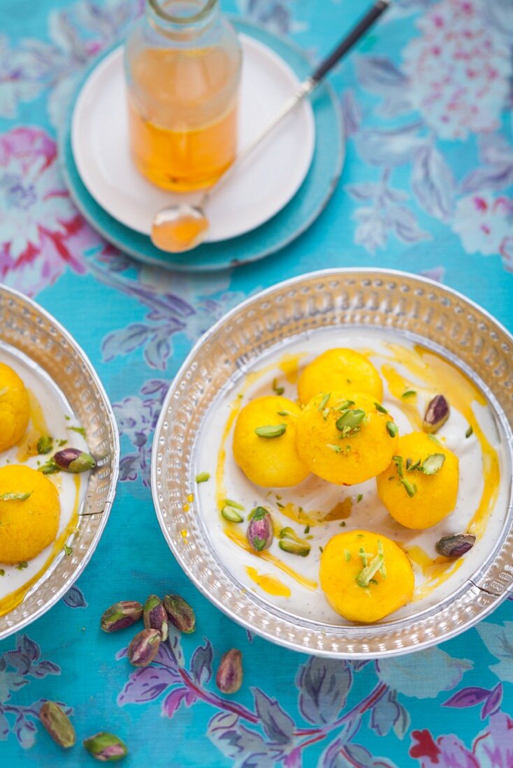 Milk balls with saffron in yoghurt with pistachios and sugar syrup