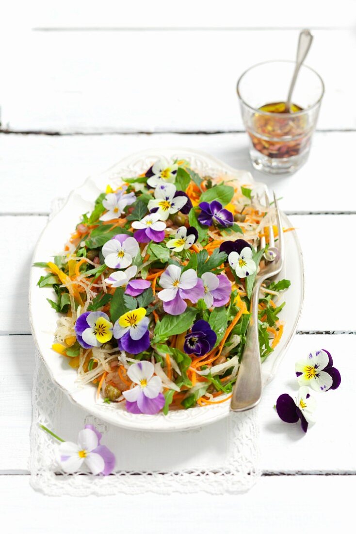 Vegetable salad (kohlrabi, yellow pepper, carrots, rocket) with parsley, basil and pansies