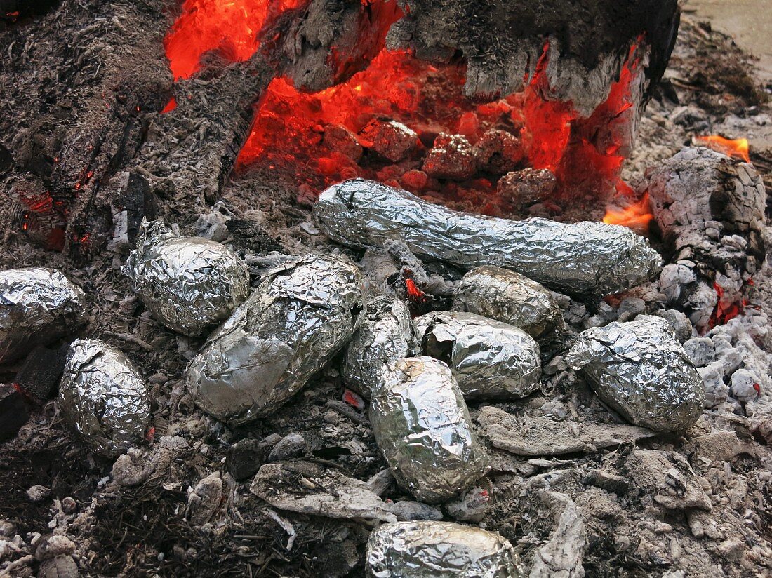Baked potatoes in the embers of a campfire