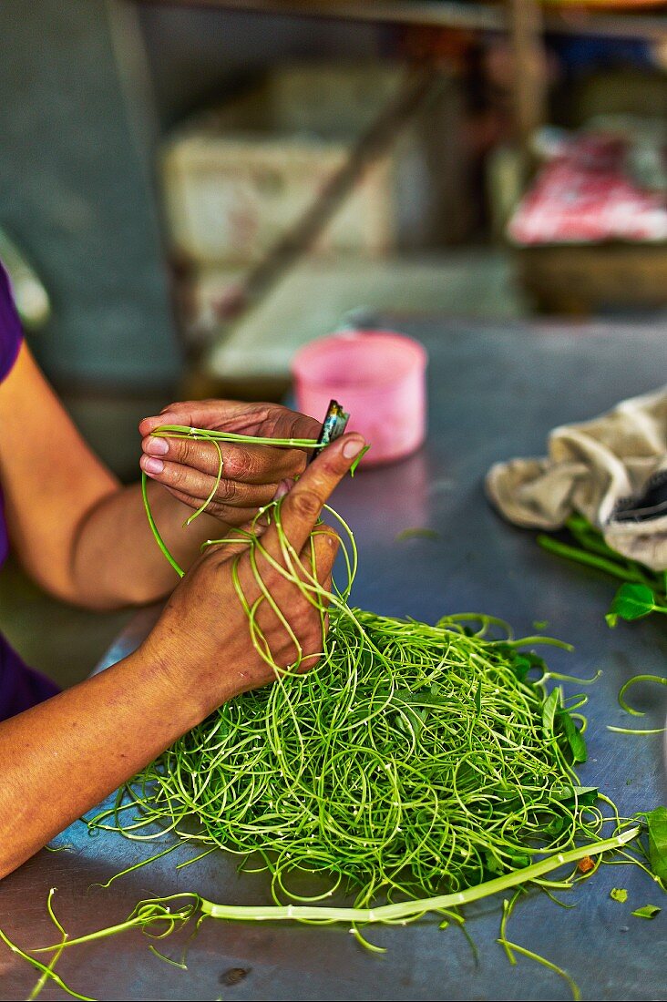 A woman cutting vegetables at a market in Haiphong, Vietnam