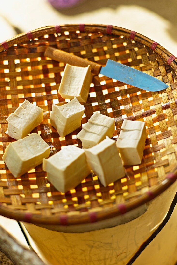 Tofuwürfel mit Messer in Bambus-Sieb