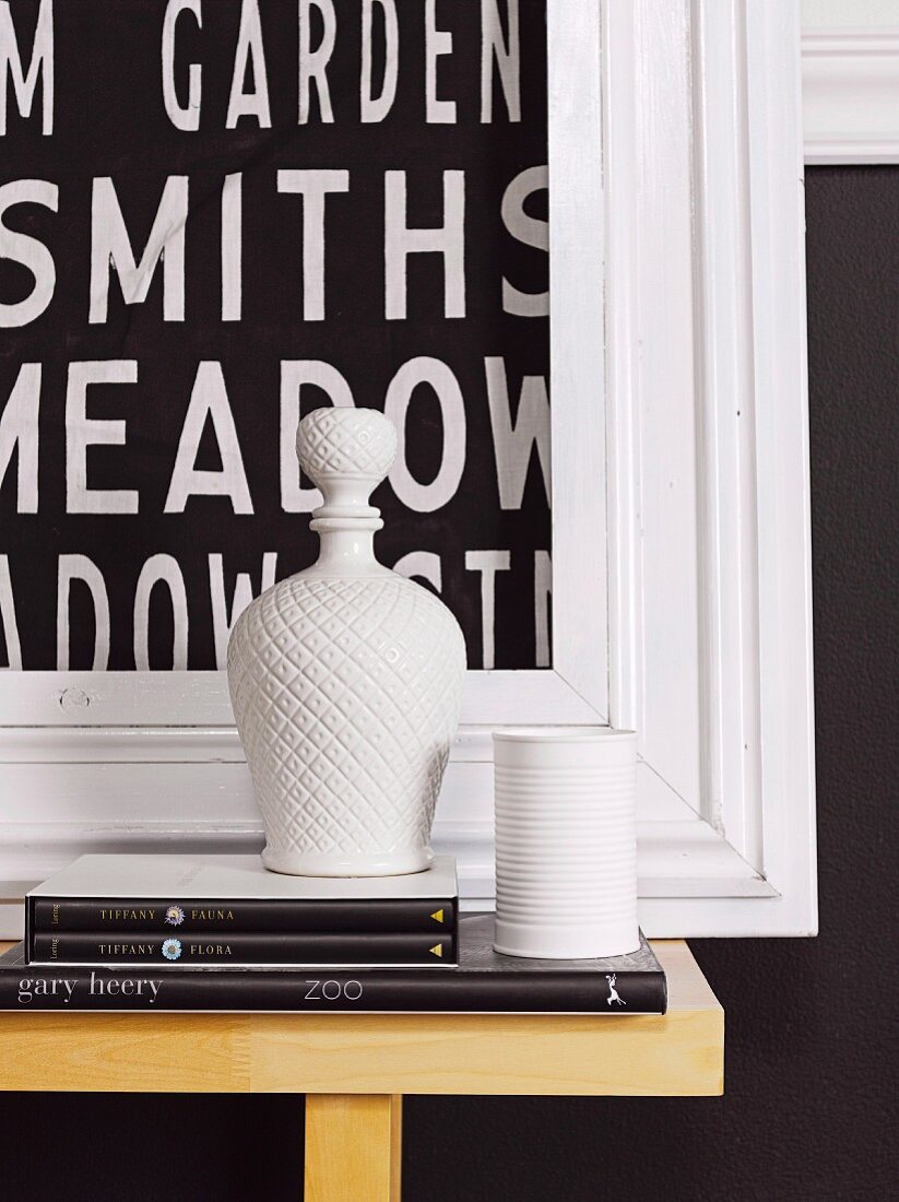 White china vessels in front of framed picture with lettering motif