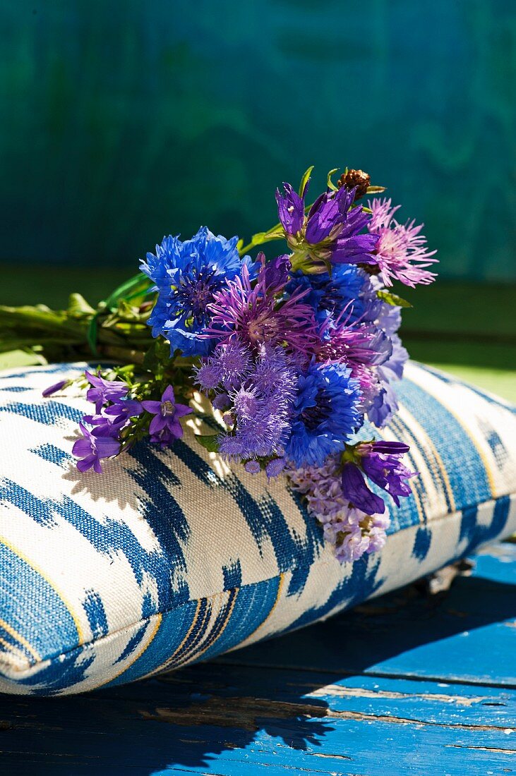 Posy of cornflowers on blue and white patterned cushion
