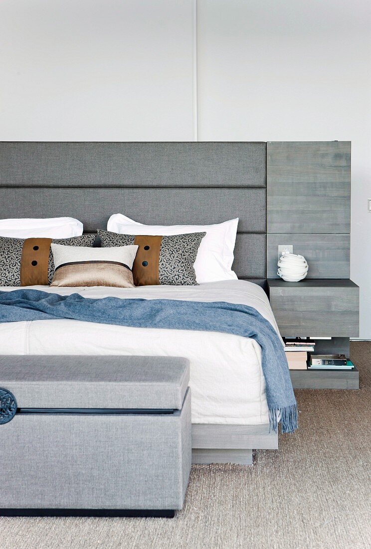 Elegant double bed with grey, upholstered headboard, integrated bedside tables and matching bedroom bench