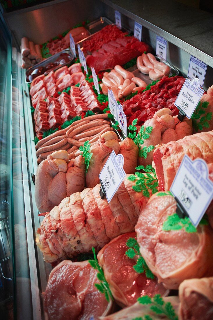 Various types of meats and sausages in a refrigerated display in a butcher's shop