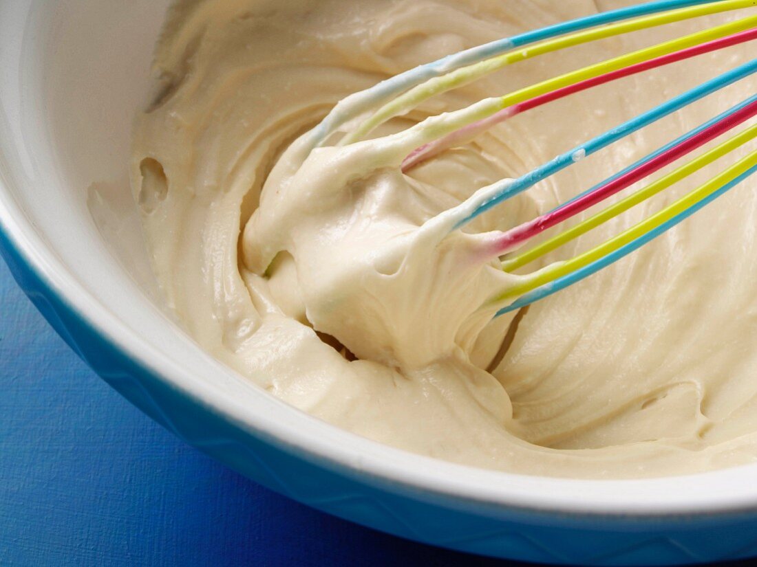 Cream cheese frosting in a bowl with a whisk
