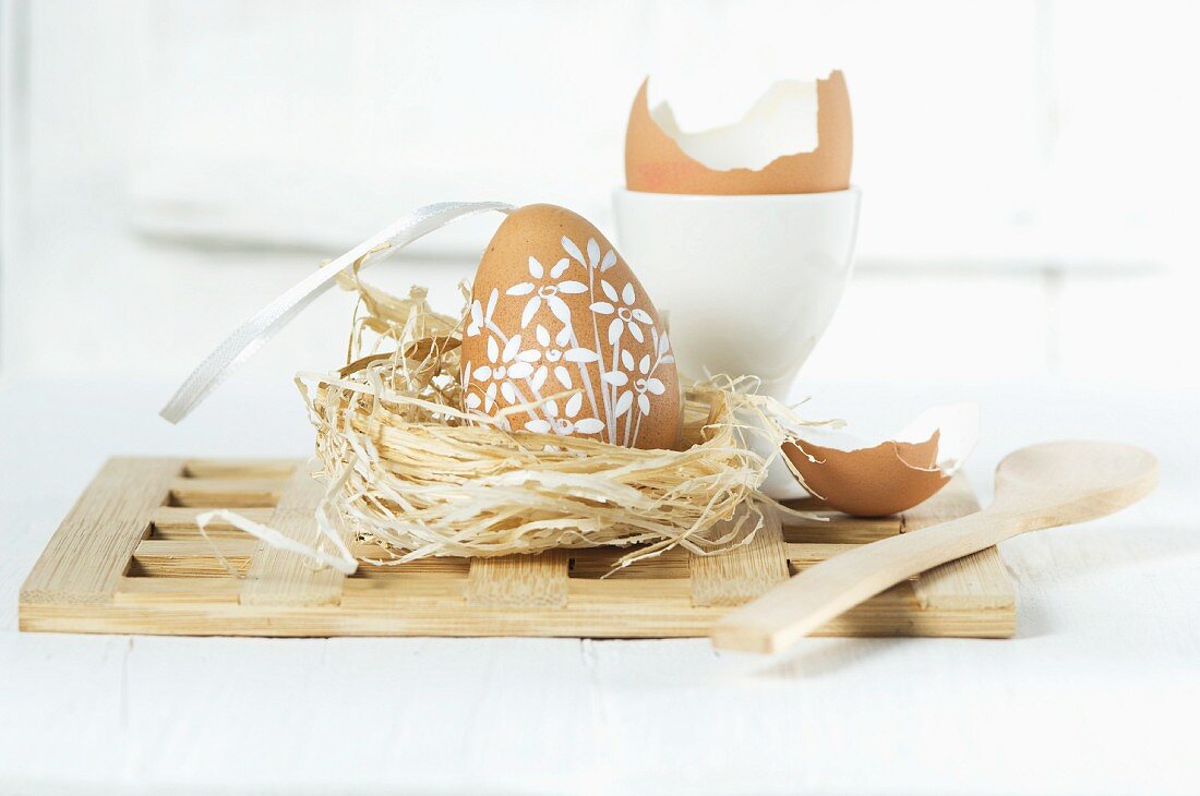 An Easter egg in straw nest with a wooden spoon