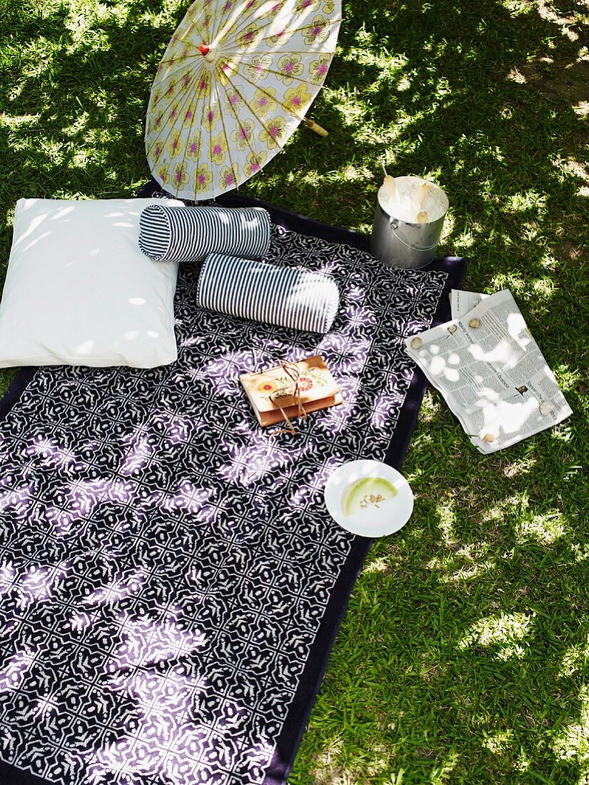 Top view of comfortable relaxation area - White and blue striped bolster on Moroccan blanket below paper parasol