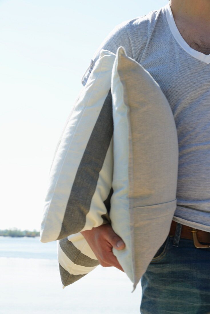 Mann mit zwei Kissen am Strand