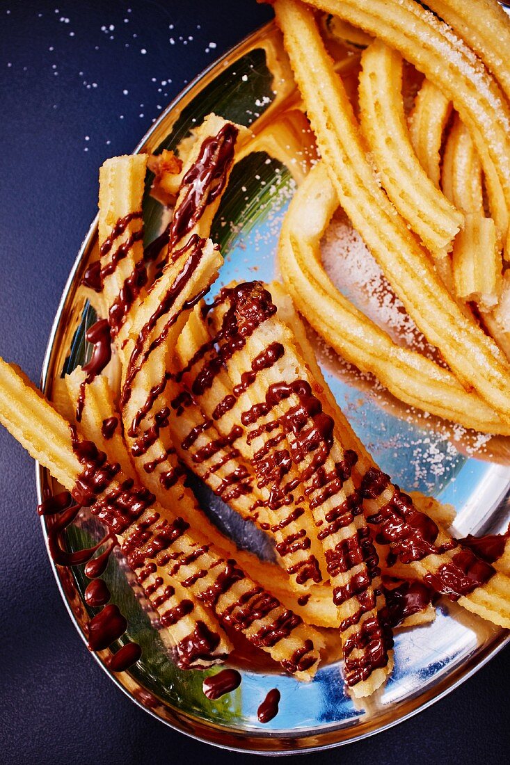 Churros (fritiertes Spritzgebäck, Spanien, Mexiko) teils mit Schokosauce