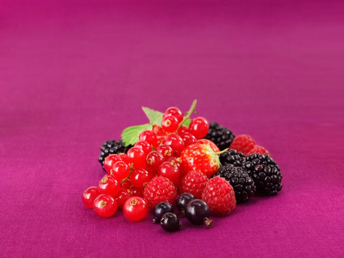 Mixed fresh berries on a purple surface