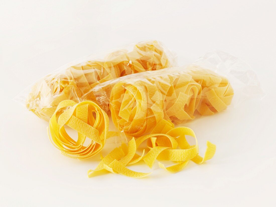 Tagliatelle in a cellophane bag on a white surface
