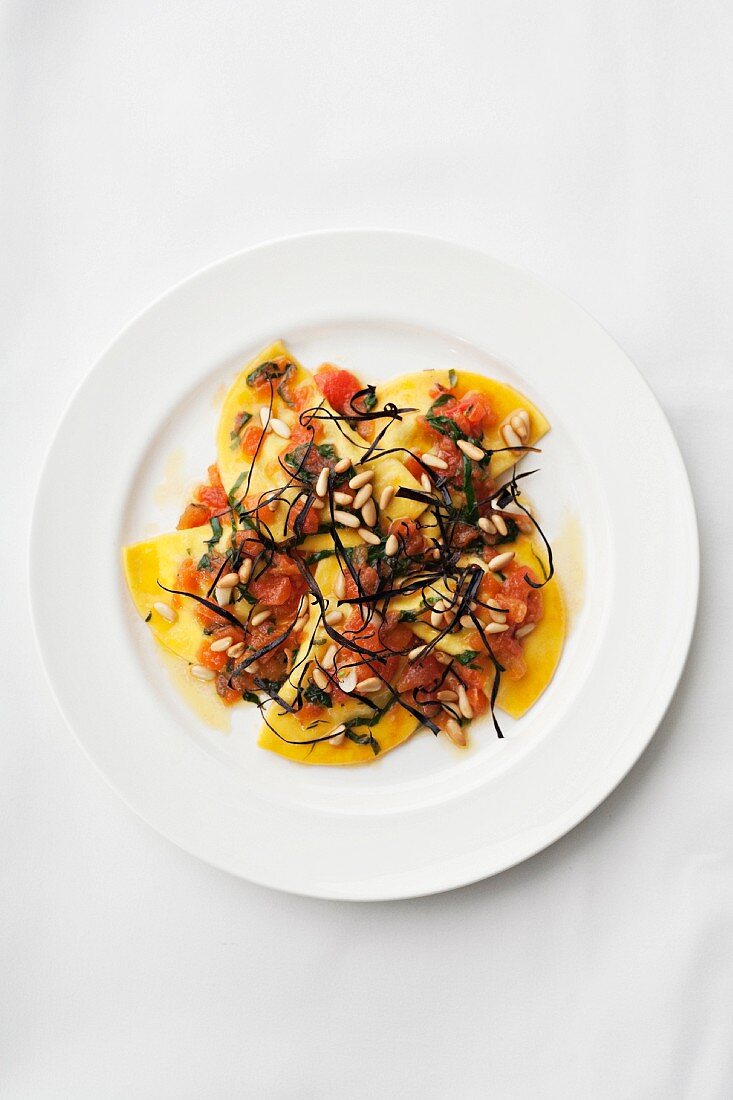 Pumpkin ravioli with tomatoes and pine nuts (seen from above)