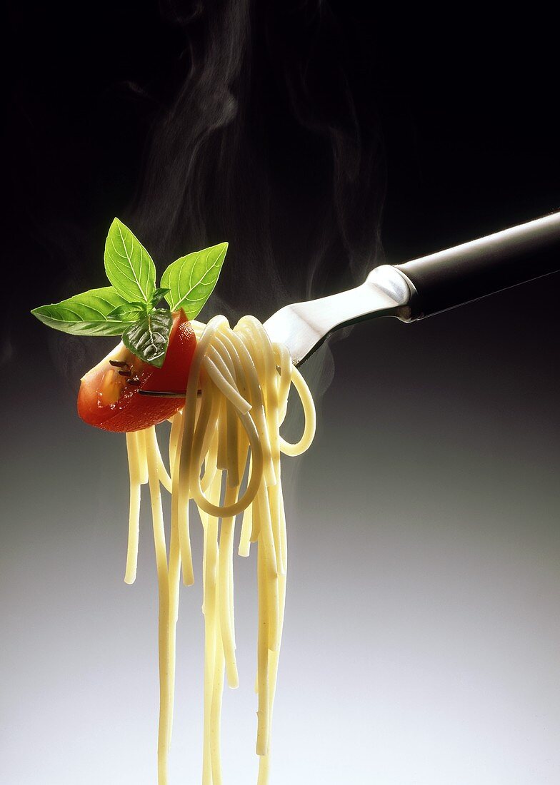 Cooked spaghetti with tomato quarter and fresh basil