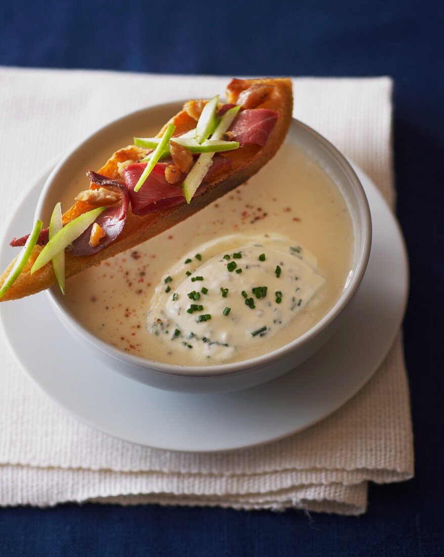 Cream of celery soup with a slice of bread topped with ham