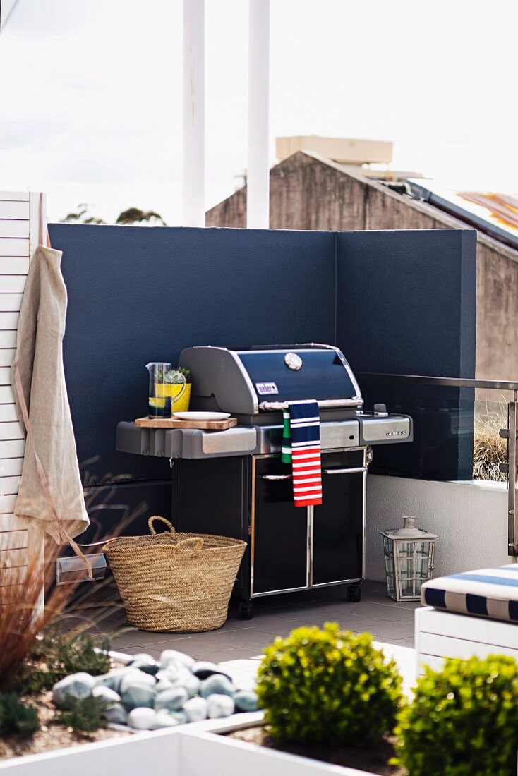 Barbecue against screen wall painted dark blue on modern roof terrace