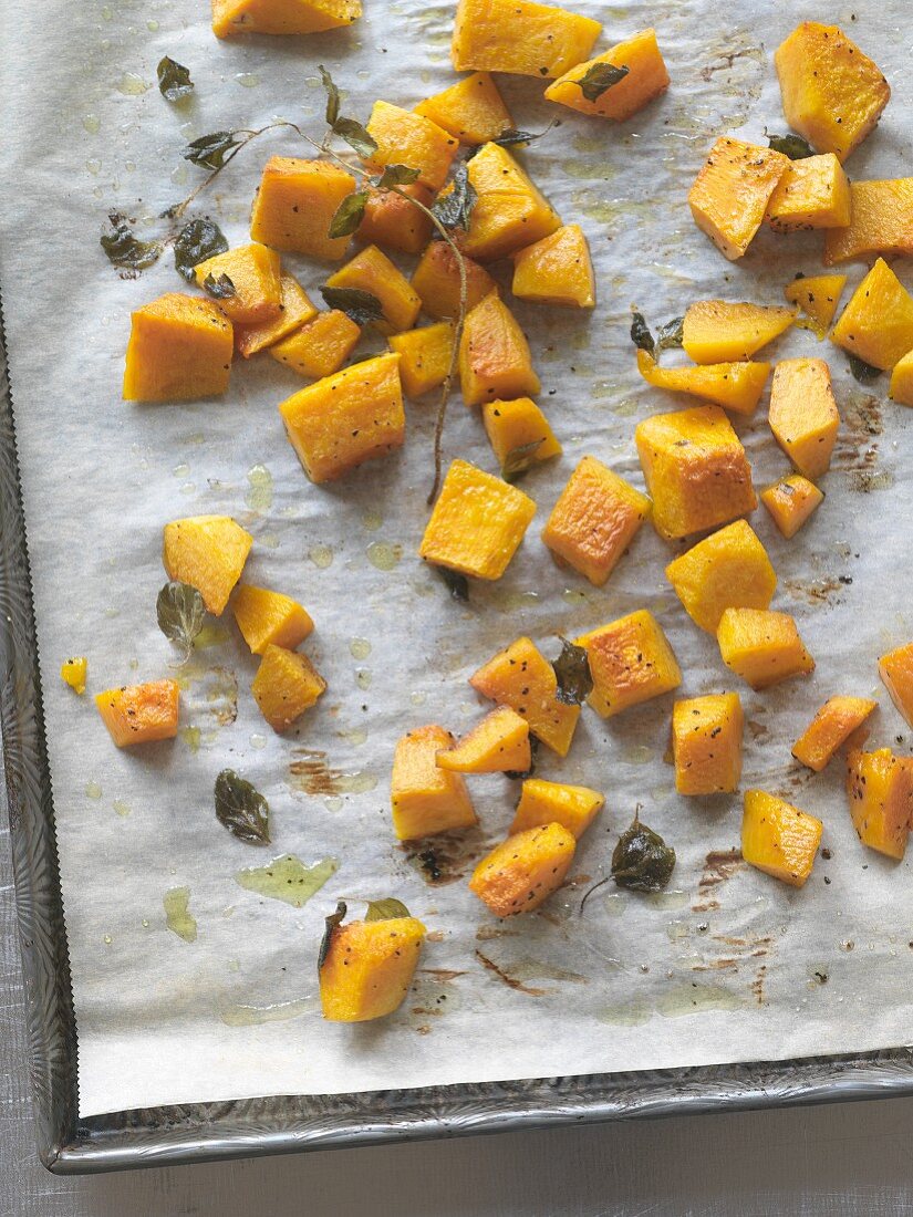 Roasted diced squash with herbs on a baking tray