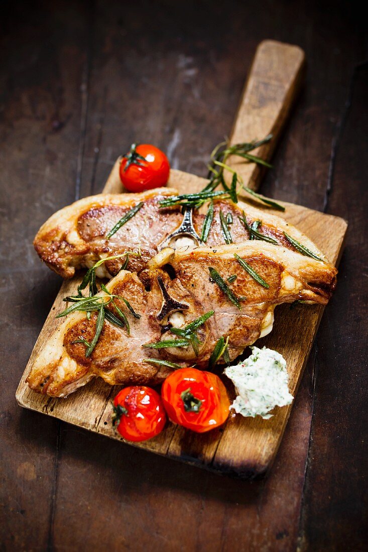 Lamb chops with rosemary and tomatoes on a chopping board