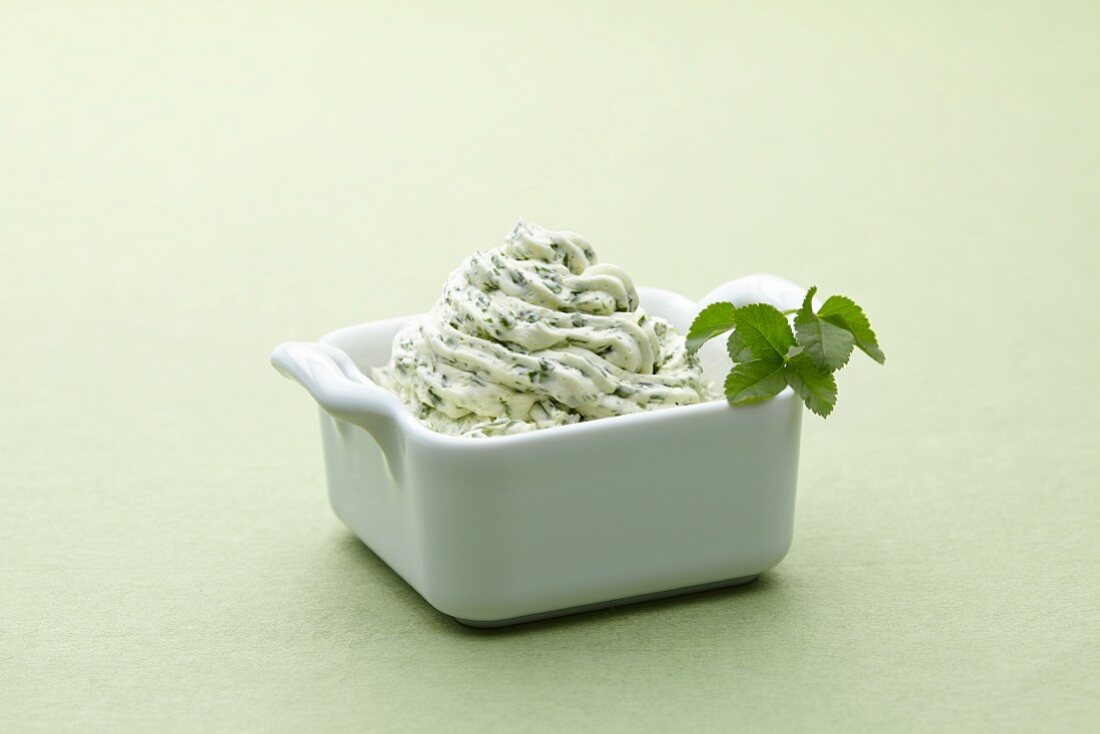 A bowl of herb butter against a white background