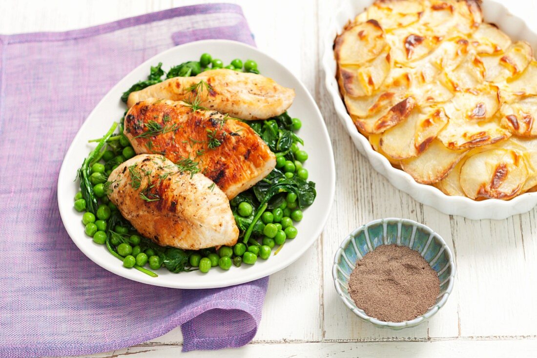 Chicken breast on a bed of peas and spinach served with potato gratin