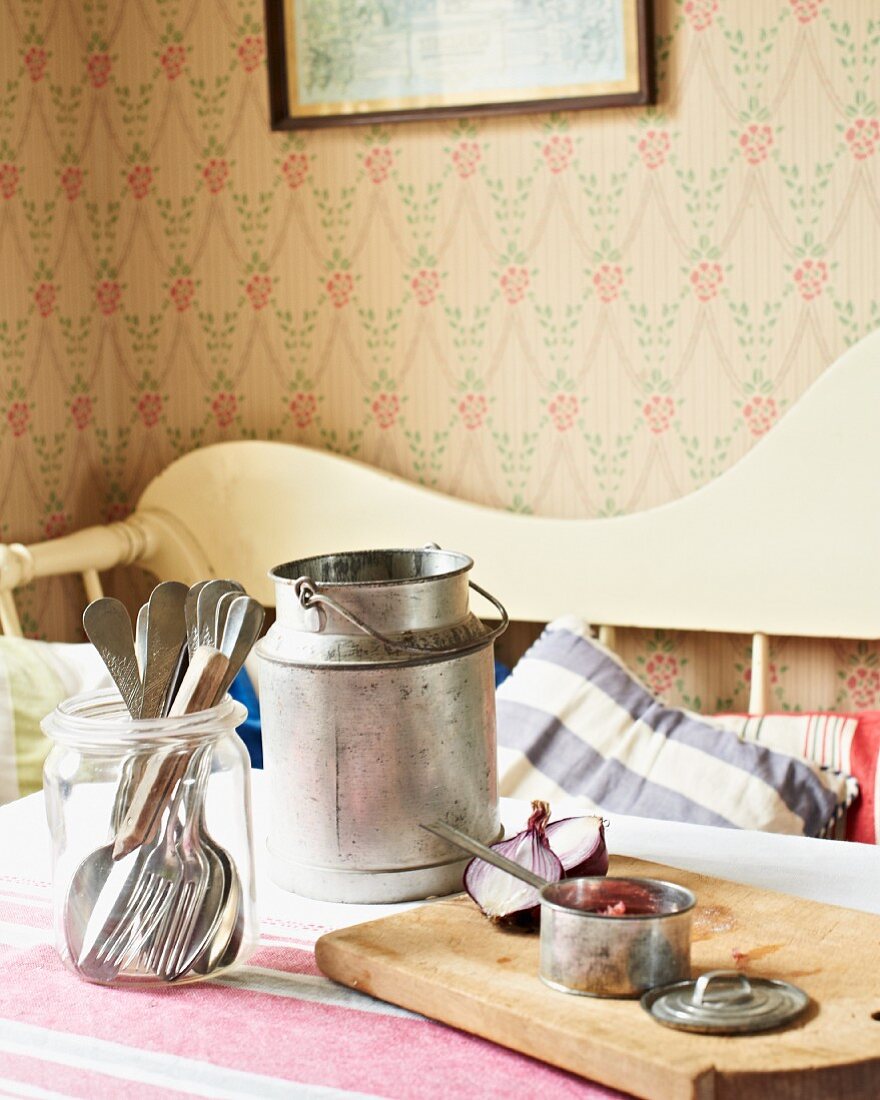 Milk churn, cutlery, onions and saucepan on kitchen table