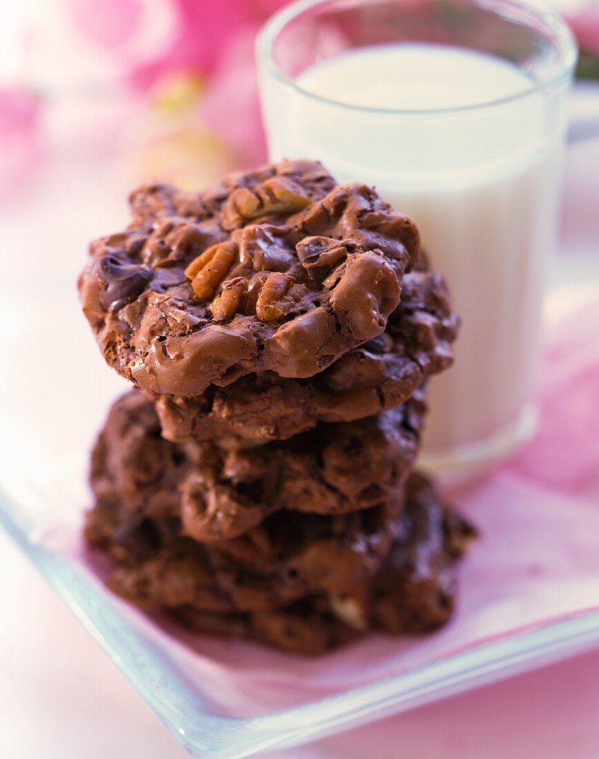 A stack of chocolate and nut cookies and a glass of milk