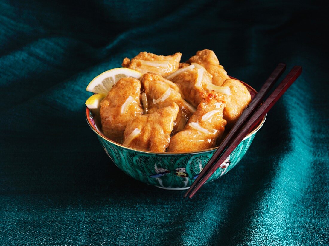Chinese lemon chicken in a bowl with chopsticks