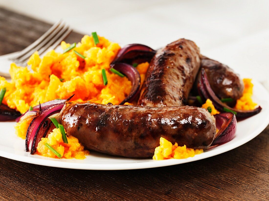 Sausages with mashed sweet potatoes and red onions