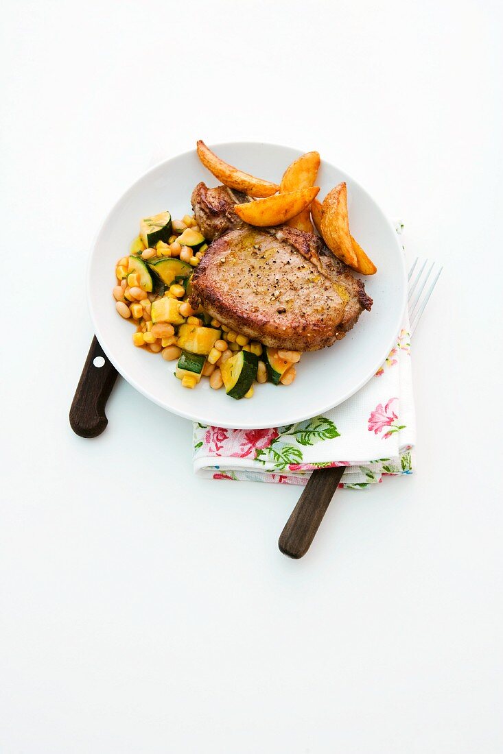 Pork chops with baked beans, courgette and potato wedges