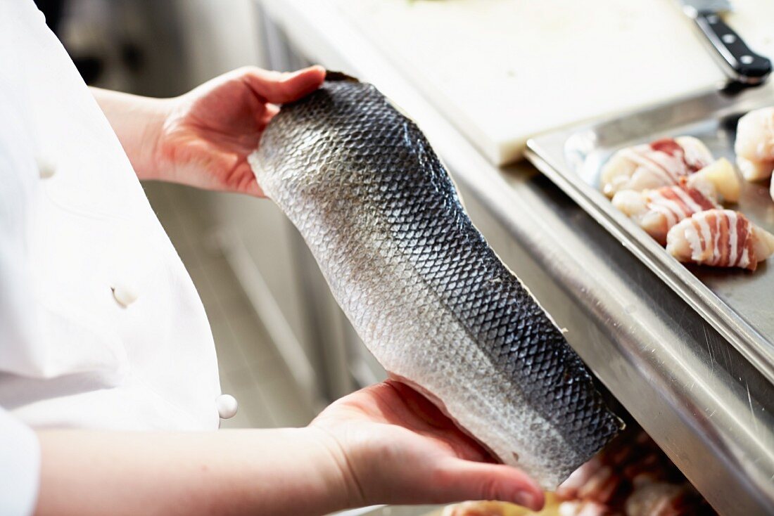 A chef holding a raw fish fillet