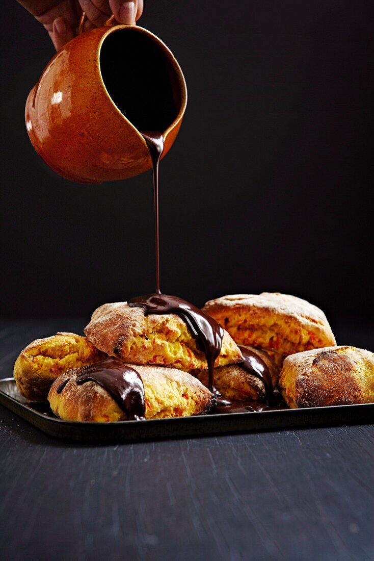 Chocolate sauce being poured over carrot rolls