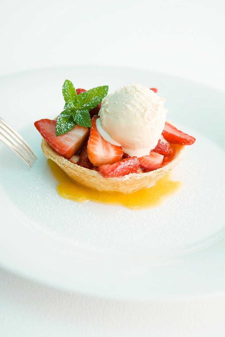A strawberry tartlet with vanilla ice cream and mint