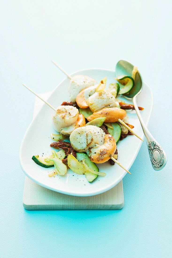 Scallop skewers on a bed of courgette and dried tomatoes