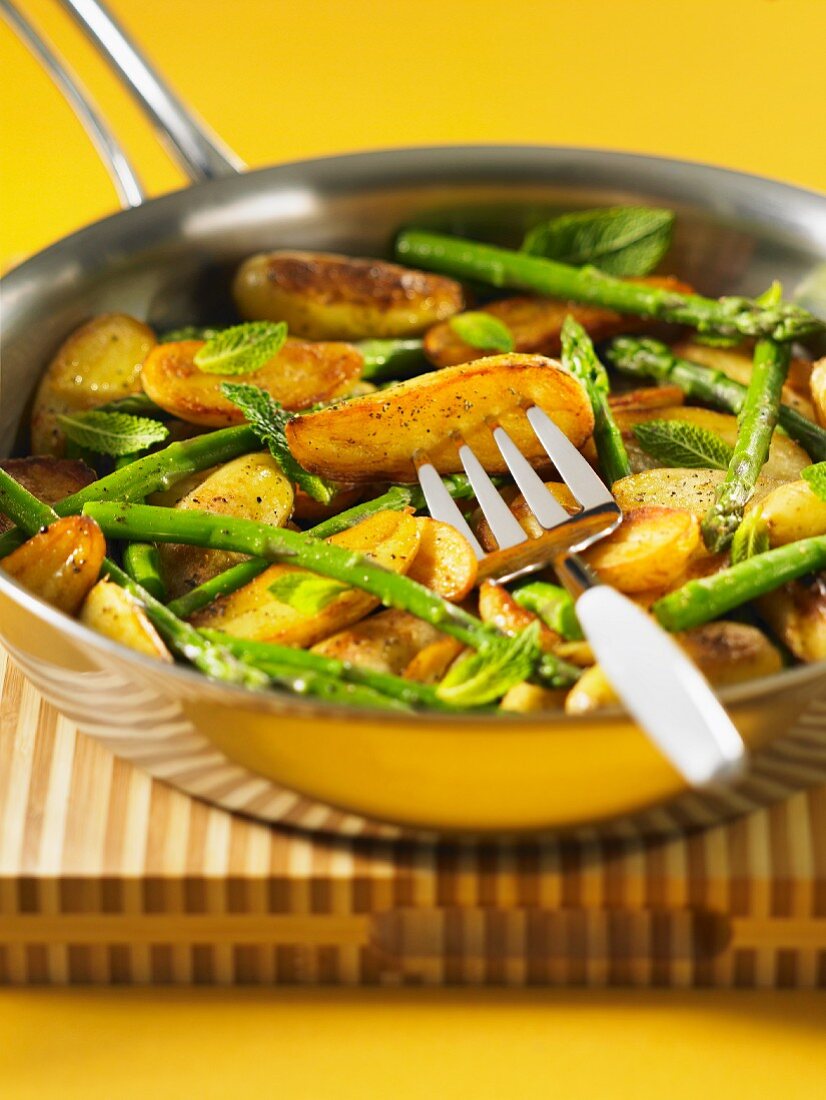 Fried potatoes with green asparagus and mint