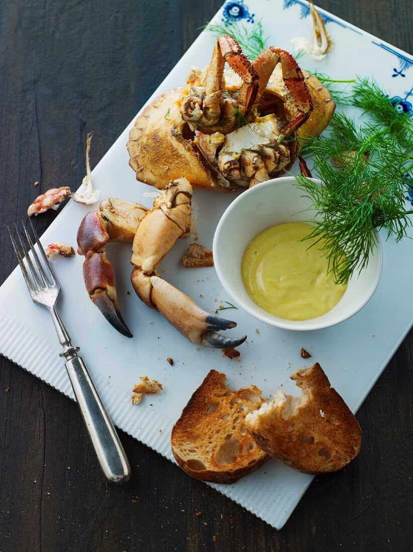 A whole crab with a dip and grilled bread