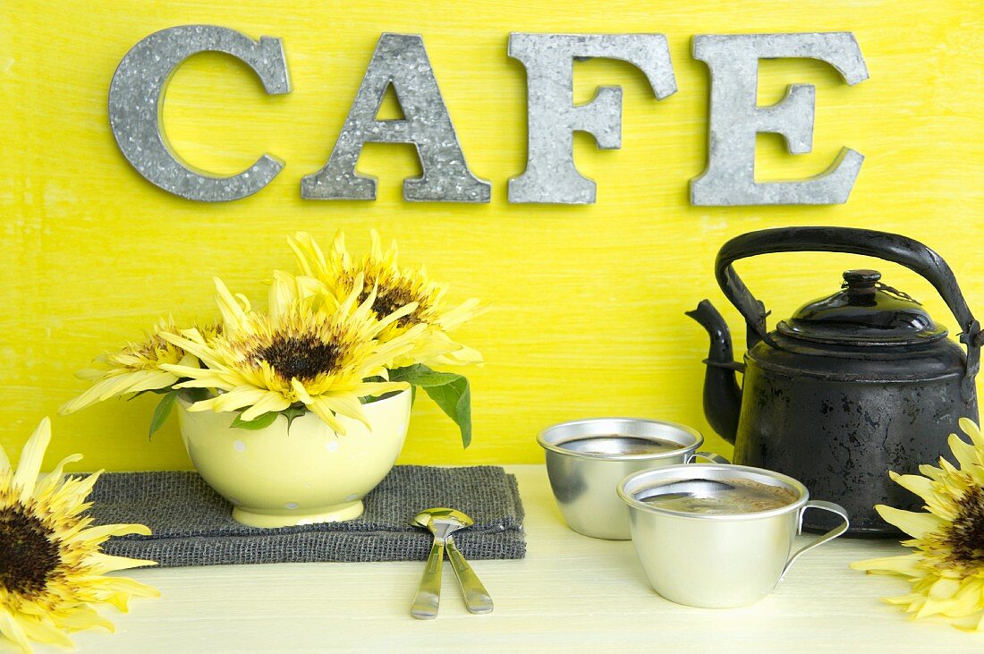 Alte Kaffeekanne, Aluminiumtassen und Sonnenblumen