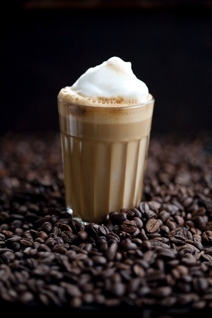 Ein Glas Latte Macchiato auf Kaffeebohnen