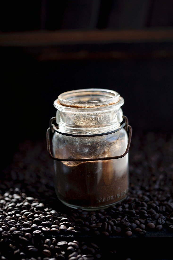 A jar of coffee powder on coffee beans