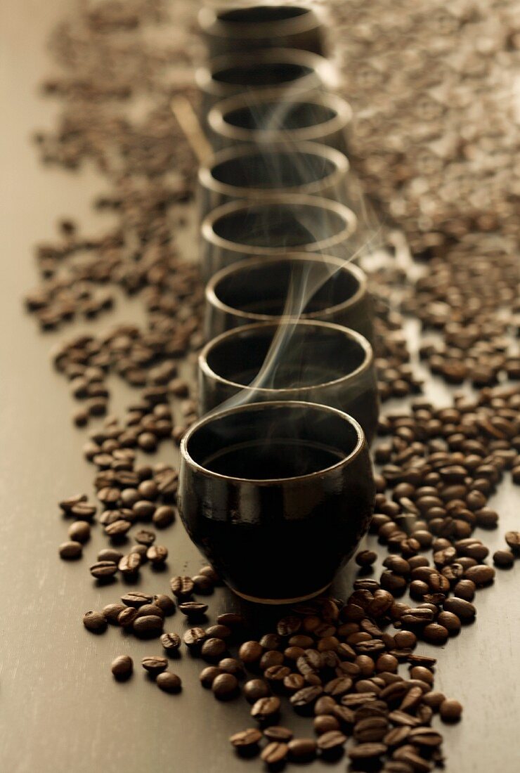 Steaming cups of coffee on coffee beans