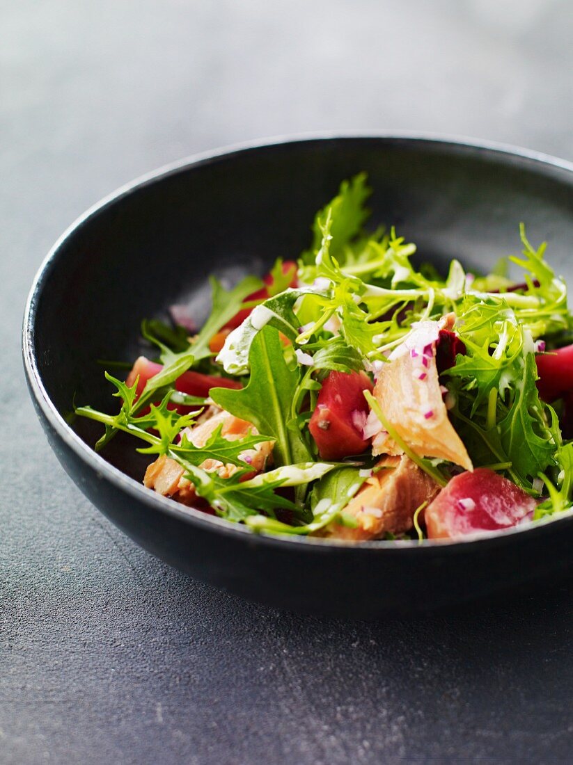 A mixed leaf salad with tomatoes and fish