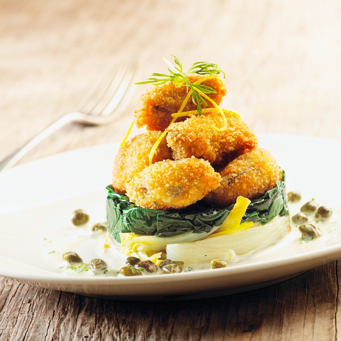 Breaded mussels with chicory on a herb and caper sauce