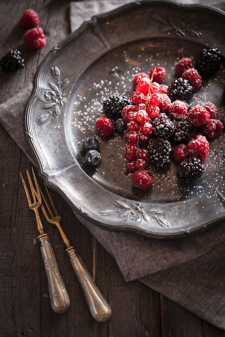 Fresh berries with sugar on a pewter plate