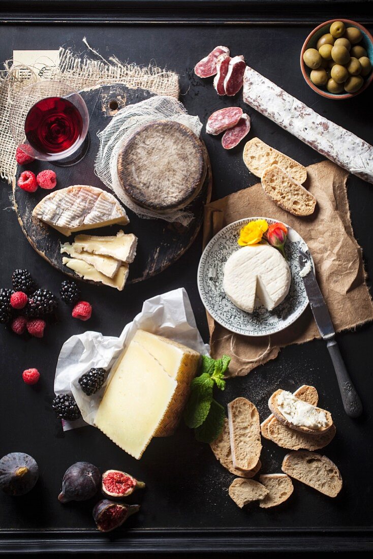 An arrangement of cheese also featuring fruit, salami, bread, olives and wine