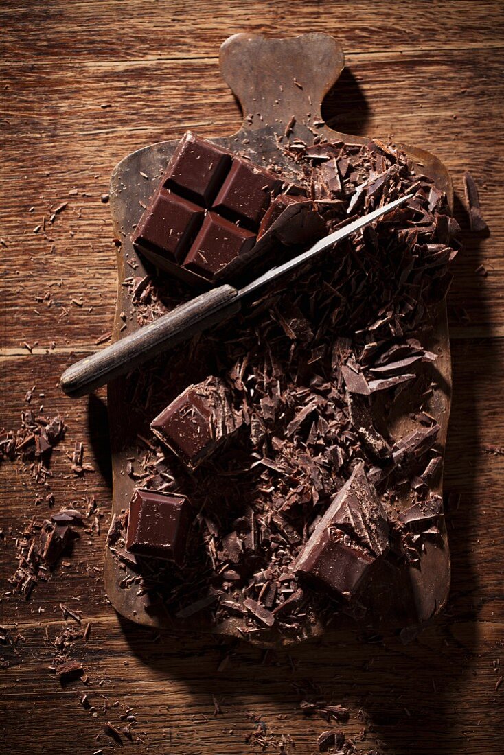 Chopped dark chocolate with a knife on a wooden board