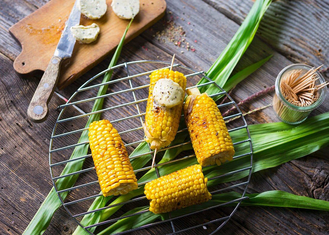 Corn cobs with pepper butter on a barbecue rack