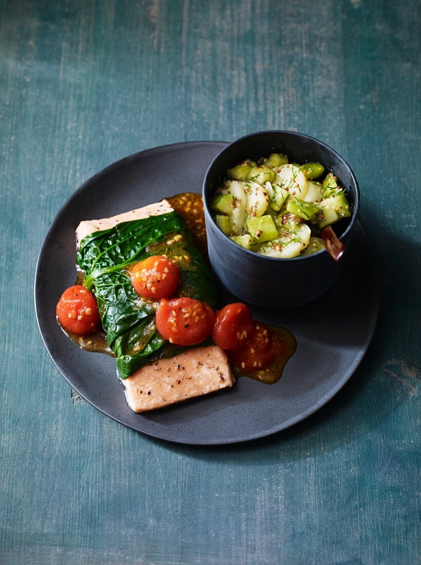 Salmon wrapped in spinach served with tomatoes