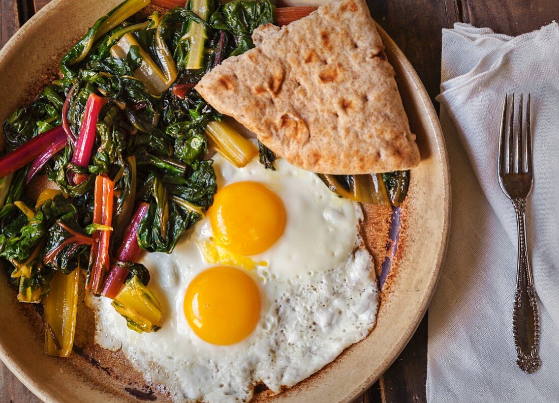 Two fried eggs with sautéed chard and unleavened bread