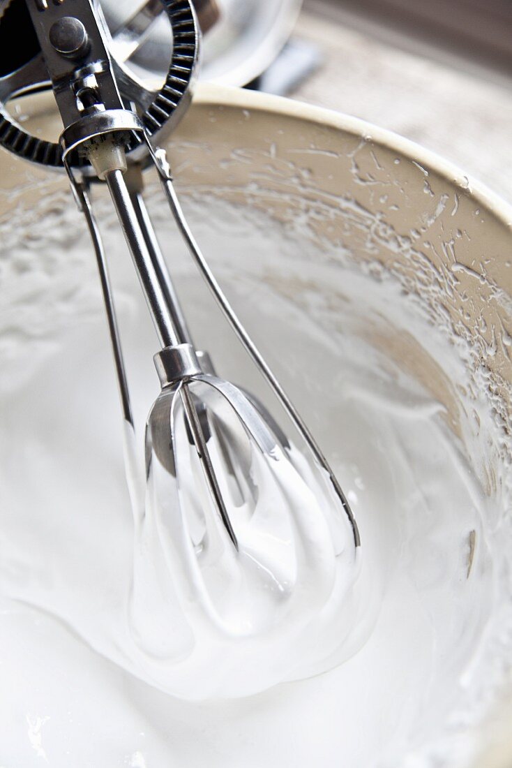 Meringue being beaten with a vintage hand whisk