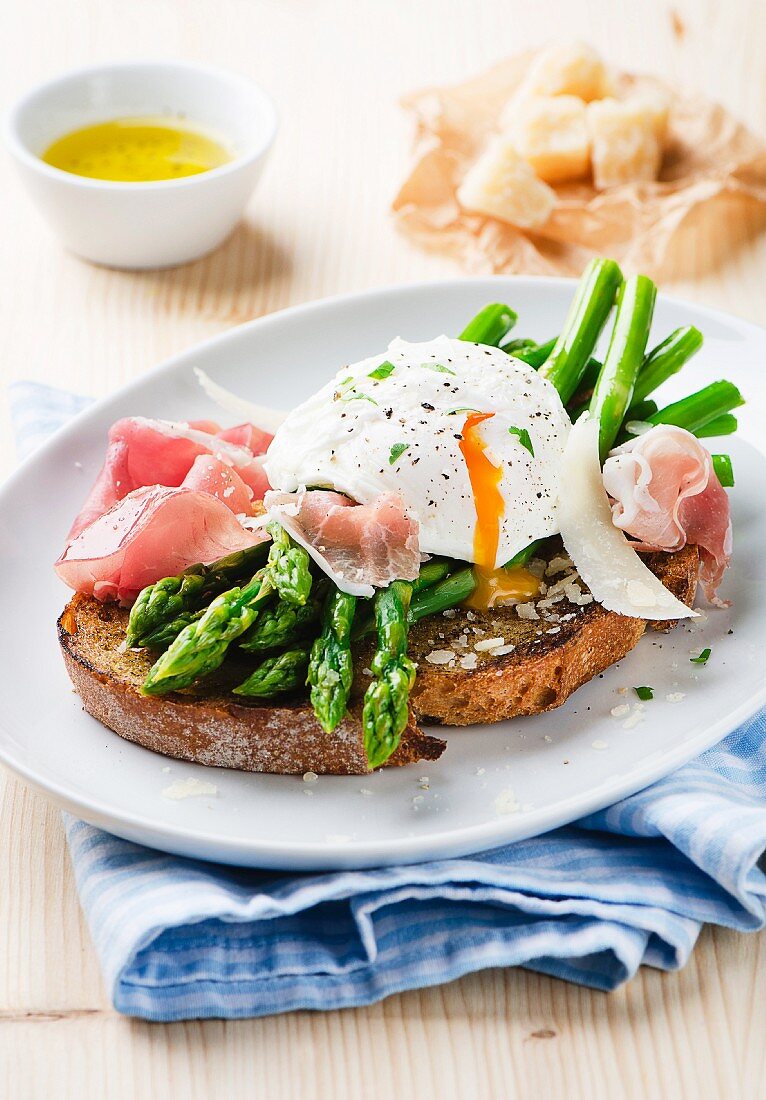 Röstbrot mit Spargel, Prosciutto, pochiertem Ei und Basilikum