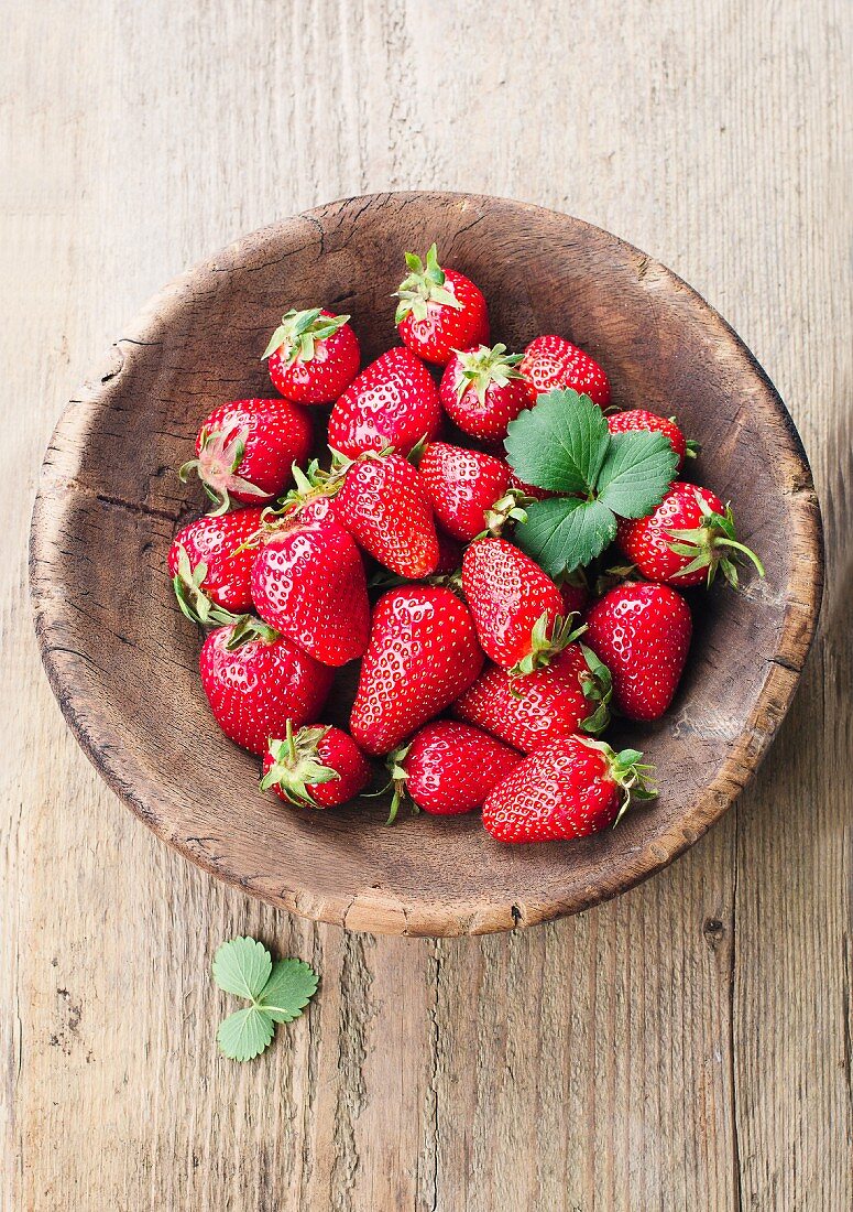 Fresh strawberries with leaves in a wooden bowl